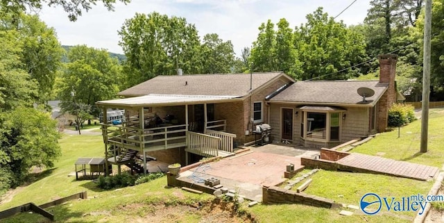 rear view of house featuring a patio, a yard, and a chimney