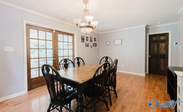 dining space featuring light wood finished floors, baseboards, crown molding, french doors, and a notable chandelier