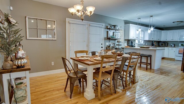 dining room featuring sink, light hardwood / wood-style floors, and a notable chandelier