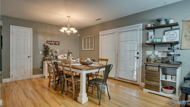 dining room with light hardwood / wood-style flooring and a notable chandelier