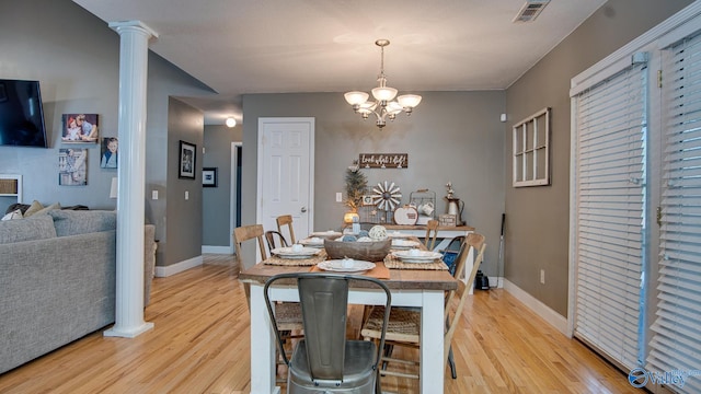 dining space with decorative columns, light hardwood / wood-style flooring, and a notable chandelier