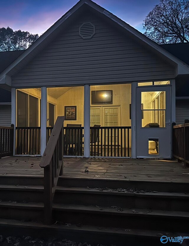 back house at dusk with a deck