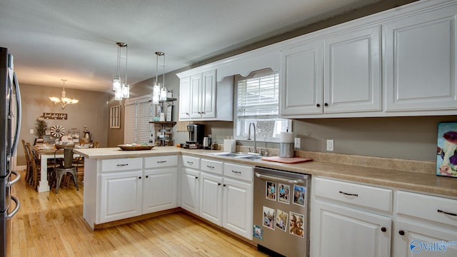 kitchen featuring kitchen peninsula, white cabinets, stainless steel dishwasher, and decorative light fixtures