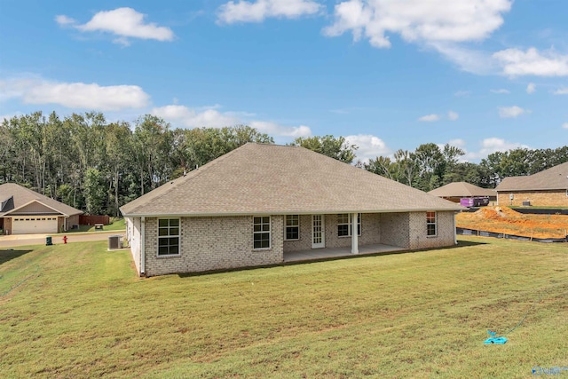 rear view of house featuring a patio, a garage, and a lawn