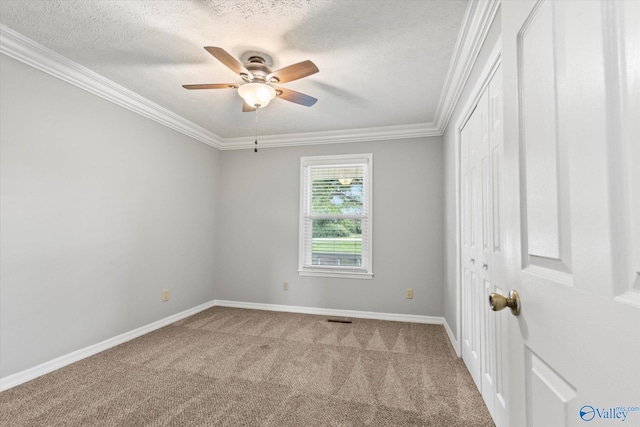 carpeted empty room featuring a textured ceiling, ceiling fan, and crown molding