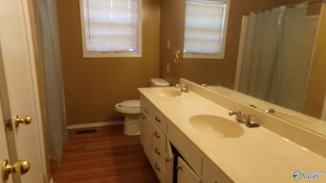 bathroom featuring toilet, baseboards, a sink, and wood finished floors