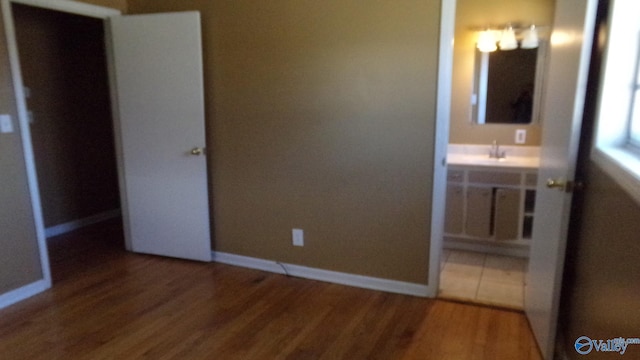 unfurnished bedroom with a sink, baseboards, and wood finished floors