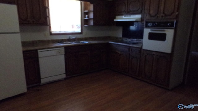 kitchen with white appliances, dark wood-style flooring, extractor fan, light countertops, and a sink