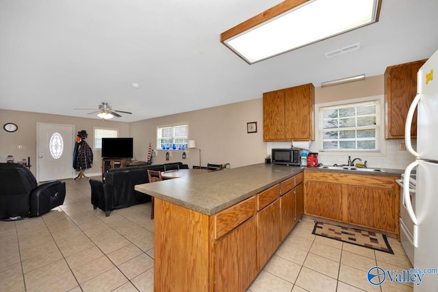 kitchen featuring light tile patterned flooring, a sink, a peninsula, visible vents, and decorative backsplash