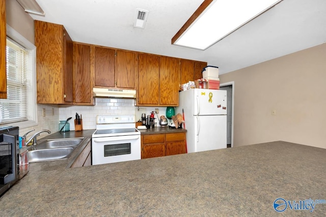 kitchen featuring visible vents, white appliances, tasteful backsplash, under cabinet range hood, and a sink