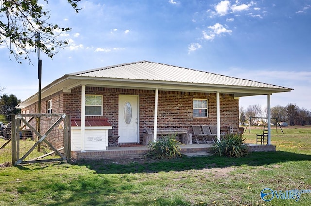 view of front of home with a patio, brick siding, metal roof, and a front yard