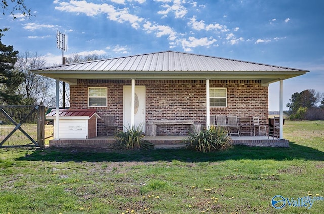 rear view of house with a lawn, metal roof, and brick siding