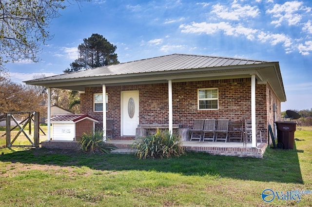 view of front of property featuring metal roof, brick siding, a front lawn, an outdoor structure, and a patio area