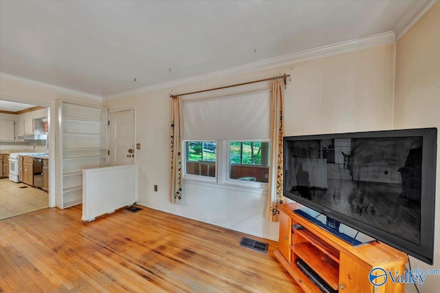 living area with ornamental molding, visible vents, and light wood-style floors