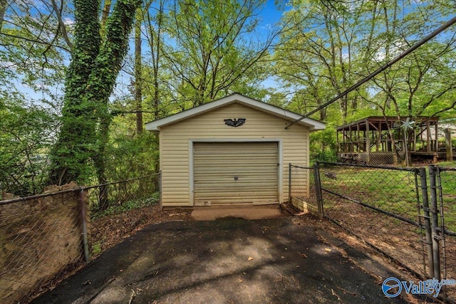 detached garage with aphalt driveway, fence, and a gate