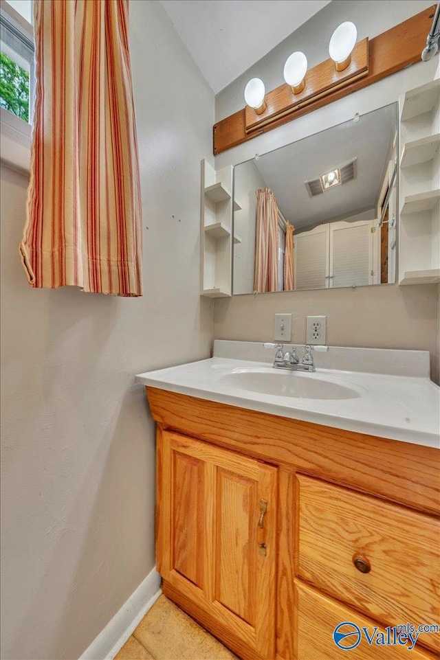 bathroom with vanity, visible vents, baseboards, and lofted ceiling