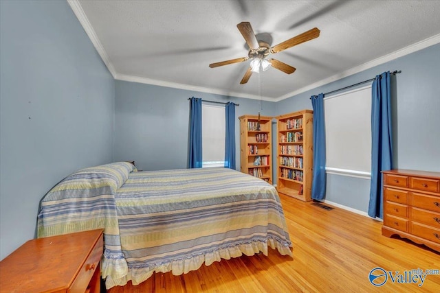 bedroom with light wood-style floors, crown molding, a ceiling fan, and visible vents
