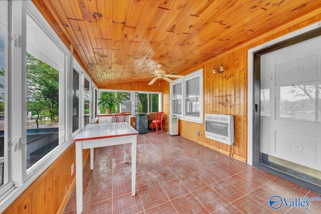 unfurnished sunroom with vaulted ceiling, heating unit, wood walls, ceiling fan, and wood ceiling