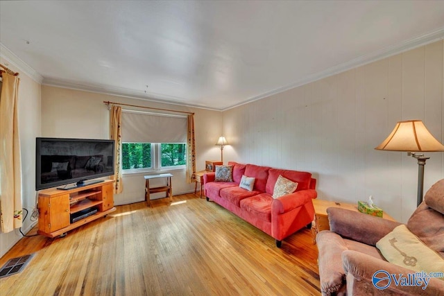 living area with wood finished floors, ornamental molding, and visible vents