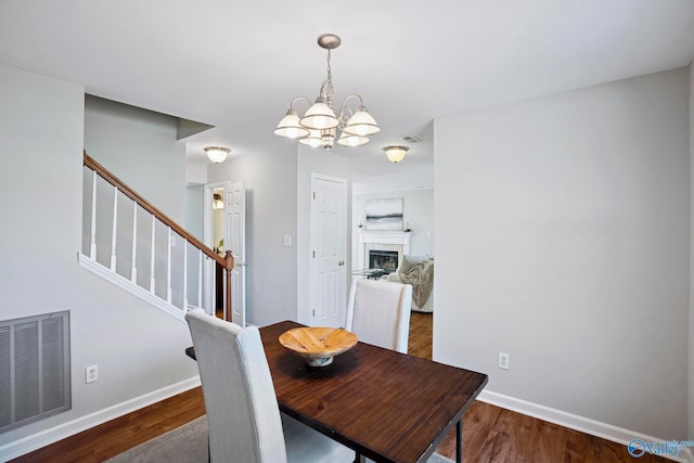 dining space with visible vents, baseboards, wood finished floors, and stairs