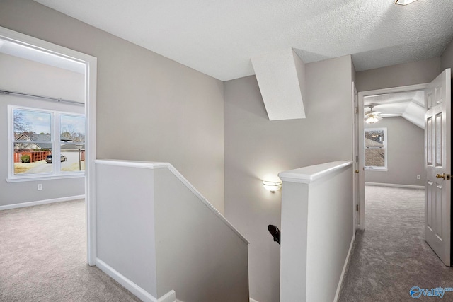 hallway with carpet, vaulted ceiling, an upstairs landing, and baseboards