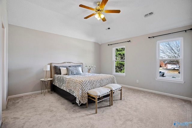 carpeted bedroom featuring visible vents, baseboards, a ceiling fan, and vaulted ceiling