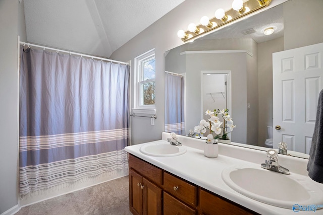 full bathroom featuring double vanity, toilet, lofted ceiling, and a sink