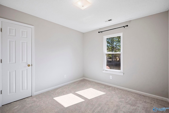 empty room with visible vents, a textured ceiling, baseboards, and carpet floors