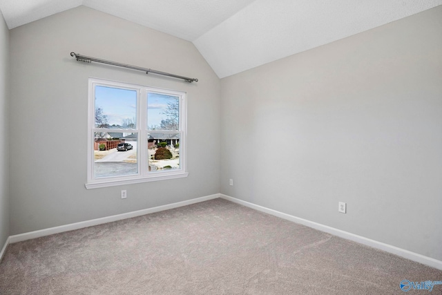 carpeted empty room featuring baseboards and lofted ceiling