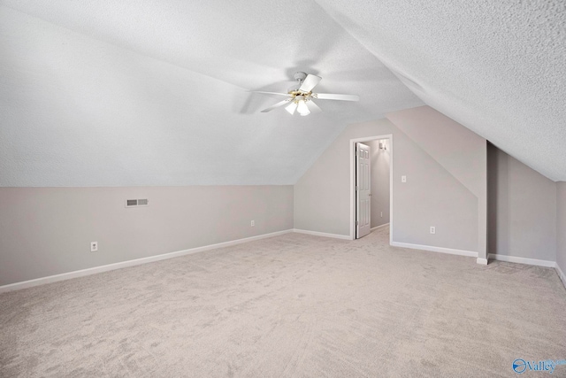 additional living space featuring vaulted ceiling, baseboards, visible vents, and a textured ceiling