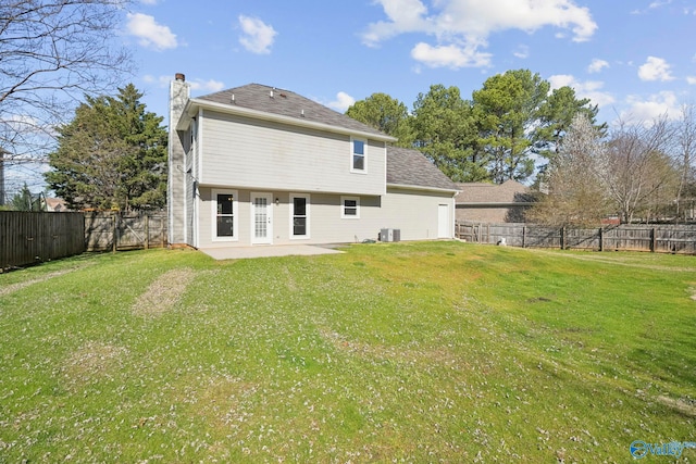 rear view of house with central air condition unit, a lawn, a chimney, and a fenced backyard