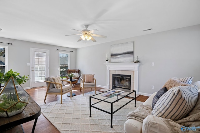 living area with visible vents, baseboards, ceiling fan, light wood-style flooring, and a fireplace