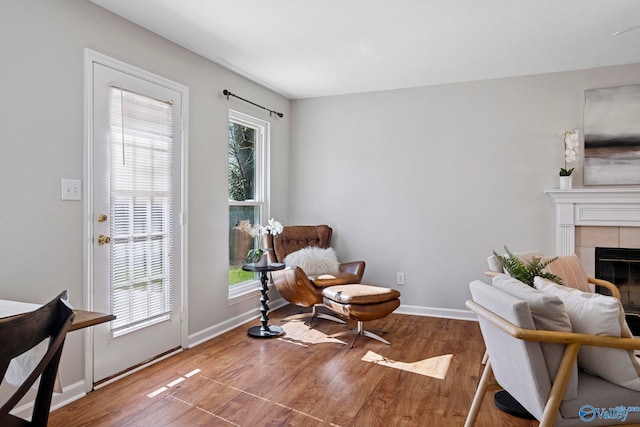 sitting room featuring a wealth of natural light, baseboards, wood finished floors, and a tiled fireplace