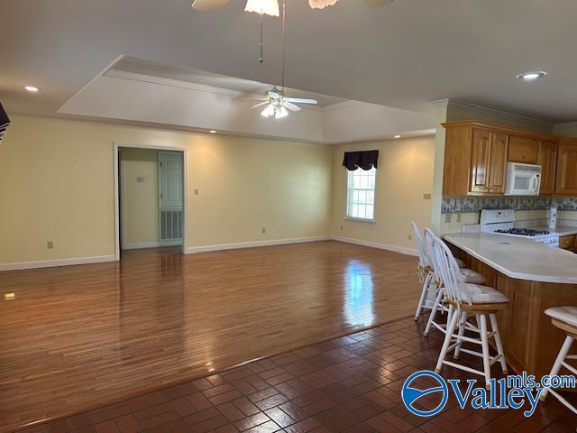 kitchen with a ceiling fan, range, white microwave, light countertops, and baseboards