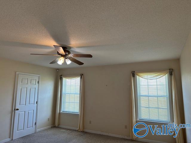 spare room with light colored carpet, baseboards, a ceiling fan, and a textured ceiling