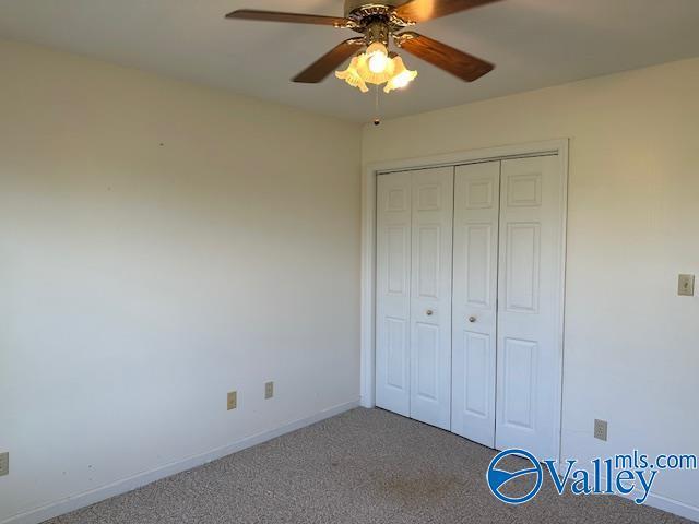 unfurnished bedroom with a ceiling fan, baseboards, carpet, and a closet