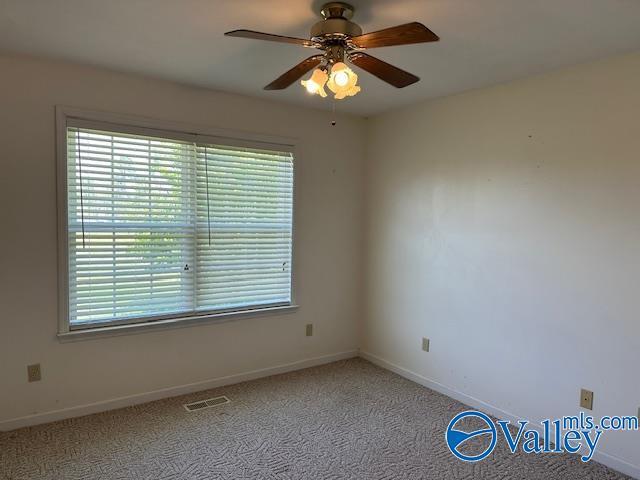 unfurnished room featuring baseboards, visible vents, ceiling fan, and carpet flooring