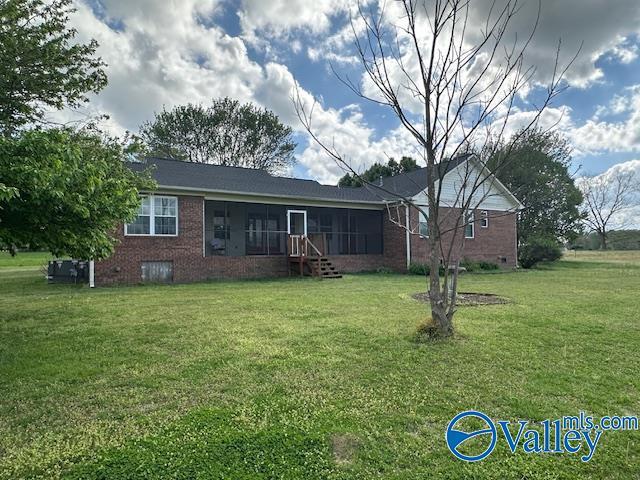 rear view of property featuring brick siding, a yard, and crawl space