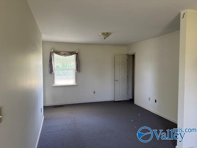 empty room with baseboards and dark colored carpet