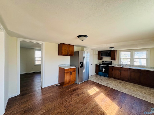 kitchen with sink, dark hardwood / wood-style flooring, a textured ceiling, and appliances with stainless steel finishes