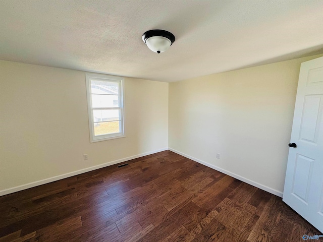 empty room featuring a textured ceiling and dark wood-type flooring