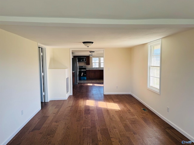 unfurnished room with dark wood-type flooring and a healthy amount of sunlight