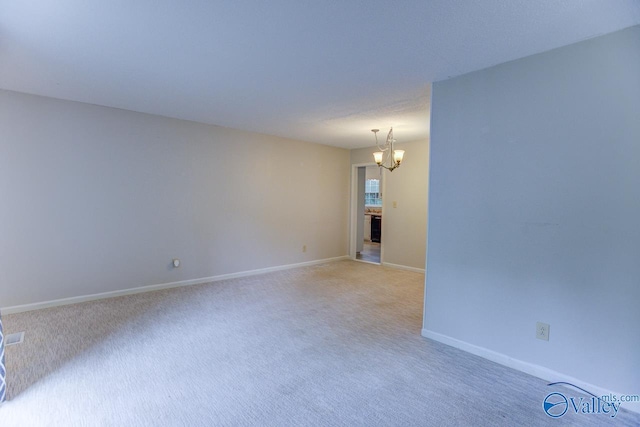 spare room with a chandelier and carpet flooring