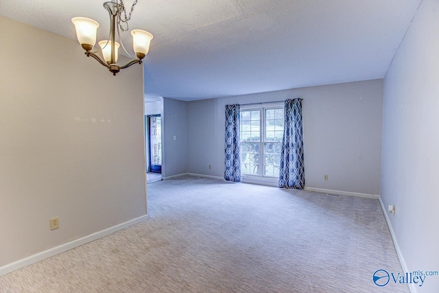 carpeted empty room with a notable chandelier and a textured ceiling