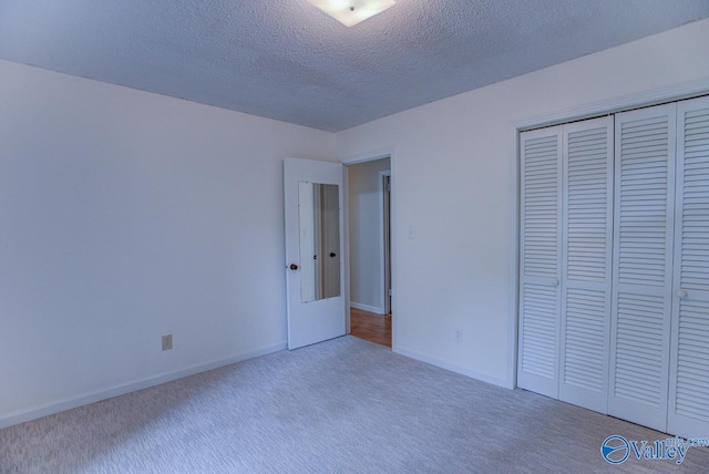 unfurnished bedroom with carpet, a closet, and a textured ceiling