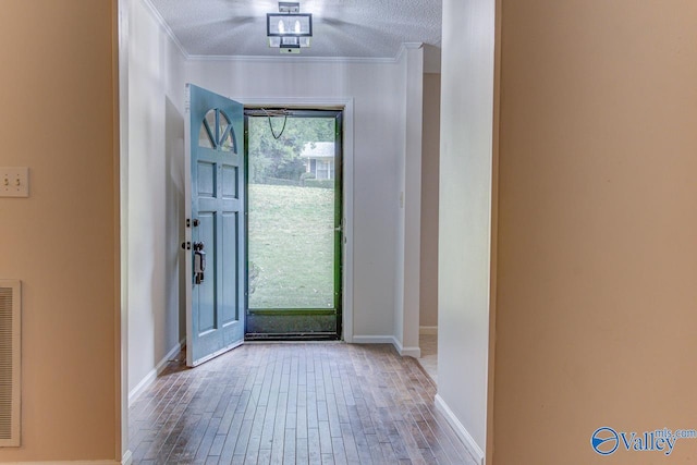 foyer entrance featuring ornamental molding, a textured ceiling, and hardwood / wood-style floors