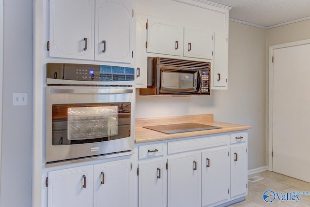 kitchen with white cabinetry, light tile patterned floors, a textured ceiling, black appliances, and ornamental molding