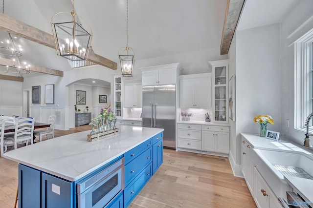 13559 Monte Vedra Rd SE, Huntsville, AL 35803 - kitchen featuring blue cabinetry, built in appliances, white cabinetry, arched walkways, and light wood-style floors