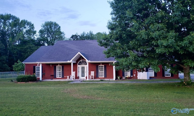 ranch-style house featuring brick siding, fence, and a front yard