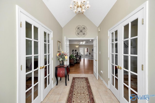 entryway with light tile patterned floors, a chandelier, vaulted ceiling, and french doors